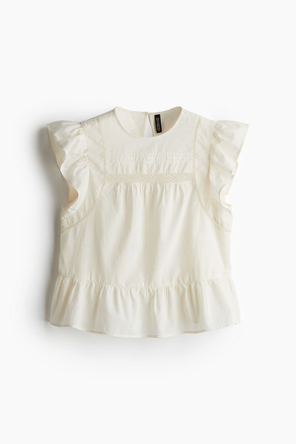 Blusa con inserciones de encaje y peplum